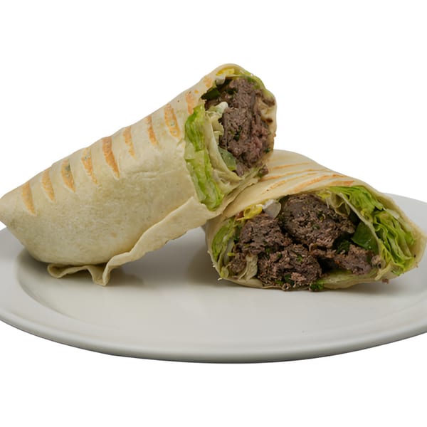 Two halves of a Black Seed Halal Grill beef and lettuce wrap on a white plate.