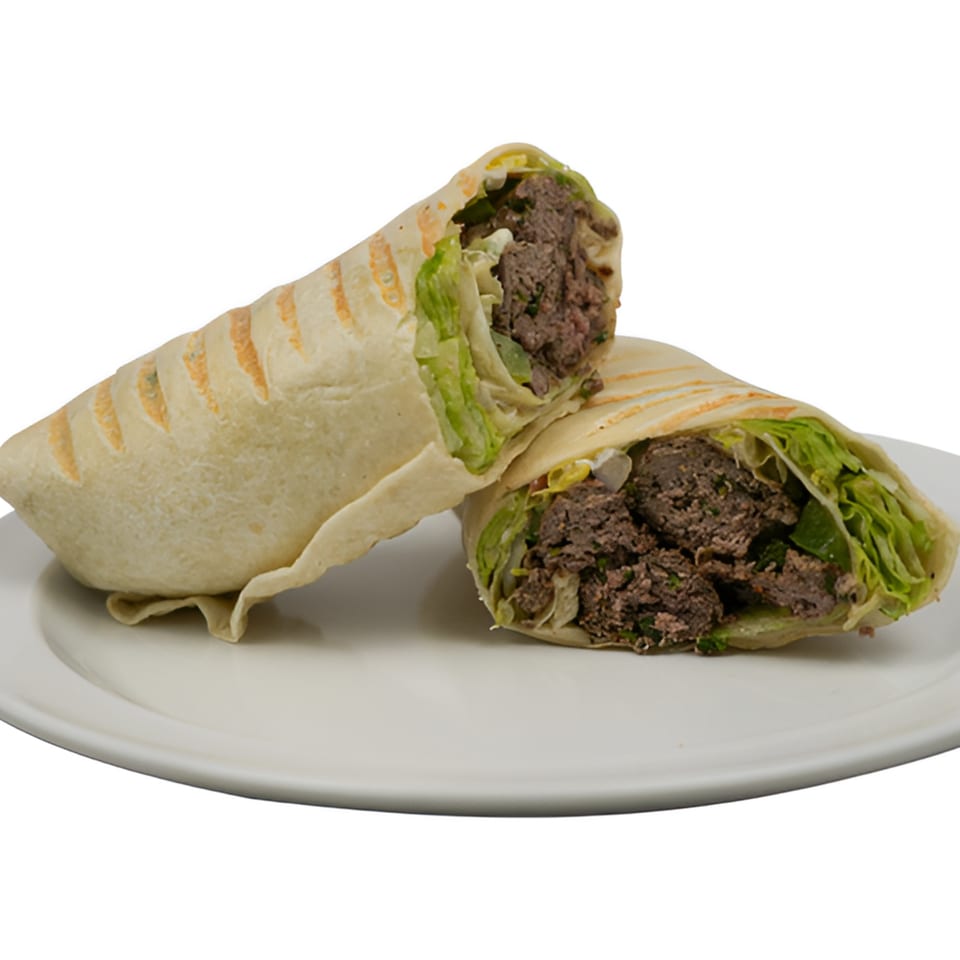 Two halves of a Black Seed Halal Grill beef and lettuce wrap on a white plate.